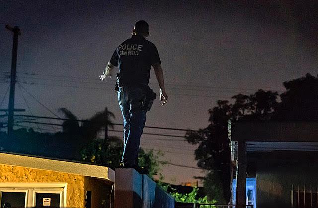 Gang detectives search a neighborhood where a suspected gang member fled when police turned down the street. Santa Ana’s Acting Chief David Valentin in mid-July began shifting officers and resources into a seven-day a week patrol to reduce street violence. 