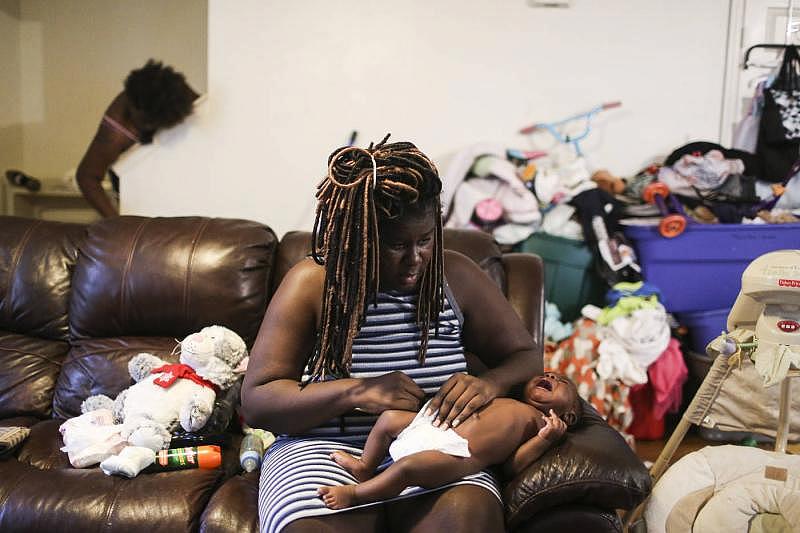 Lalandria changes Amound's diaper while her family gets ready for the day.