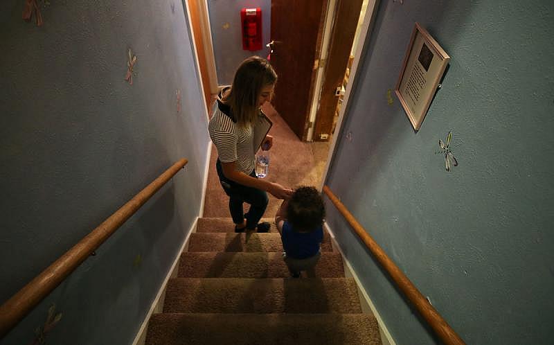 Brooke Francis, a caregiver, helps a child down the stairs towards the playroom at the KPC Respite & Nursery Center in Colorado Springs on Tuesday, May 16, 2017. Up to 72 hours of care is given at no charge with a primary purpose: giving parents a break to help prevent child abuse and neglect.