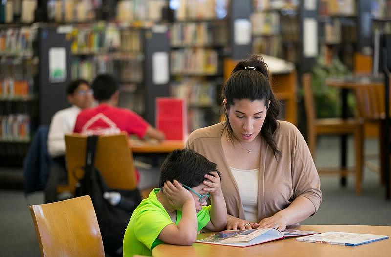 Cristine Pagan helps her son Dean with reading homework at a local library branch. When Dean started first grade at Comly Elementary last September, his classroom was filled with potentially hazardous deteriorating paint, and the school district knew it.