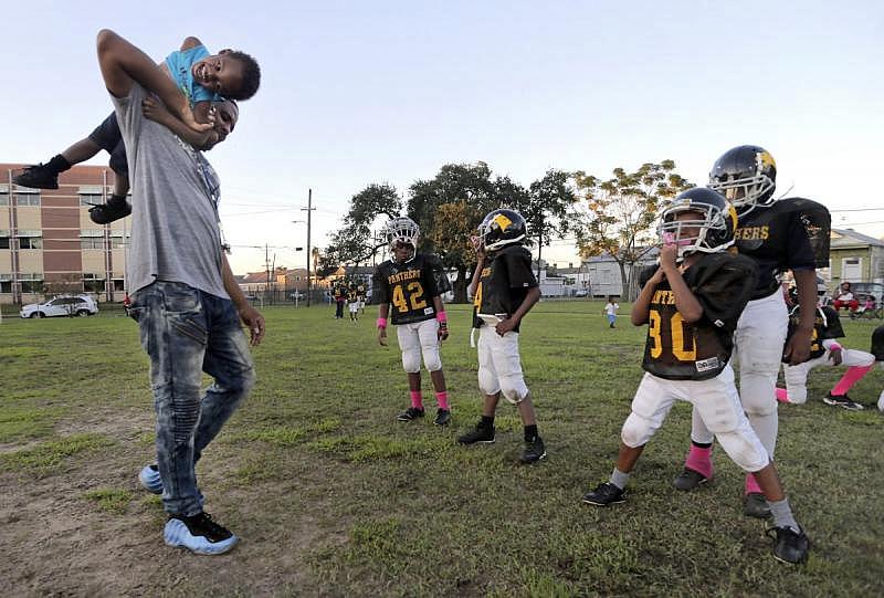 Panthers head coach Edgarson Scott carries his son Tony on his shoulders during football practice at A.L. Davis Park in Central City.