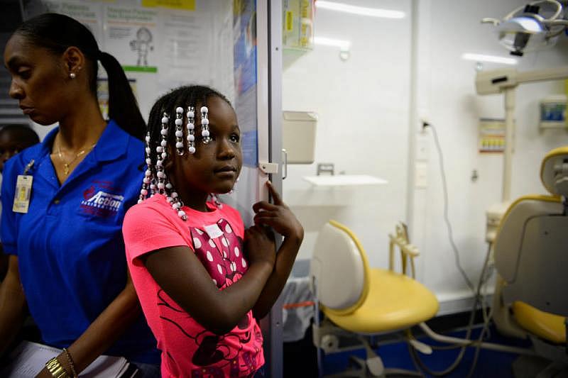 Michelle Shoates, 5, looks on from the outside of the patient room as she waits to be seen by the dentist on the dental bus. Staff Photo/Rachel S. O'Hara