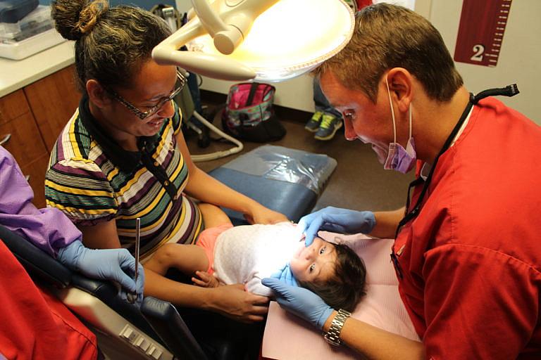 Maria Gonzalez tries to make her 11-month-old daughter Corazon Selbera, of Del Rio, Texas, smile as Dr. Howard Hunt examines her new teeth on July 11. Photo by Jamie Bridges Maria Gonzalez tries to make her 11-month-old daughter Corazon Selbera, of Del Rio, Texas, smile as Dr. Howard Hunt examines her new teeth on July 11. Photo by Jamie Bridges