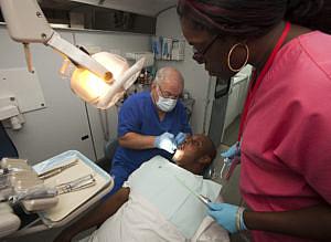 Dentist and State Sen. Alan Hays, left, prepares to remove a tooth from patient Sean Washington on the Florida Baptist Convention’s Mobile Dental Unit at the Central Florida Hampton Center car lot Wednesday morning, June 27, 2012 as dental assistant Allison Whipper, right, watches. (Doug Engle/Star-Banner)