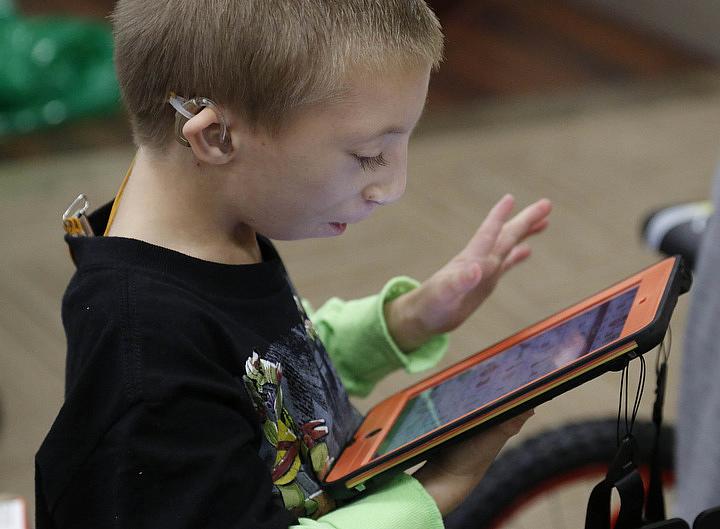 Christopher Rollins, seen here at age 9, navigates the app “ProLoquo2go” on his new iPad Mini in the conference room at the Central Florida Speech and Hearing Center in Lakeland Fla., on December 22th 2014. THE LEDGER/CALVIN KNIGHT