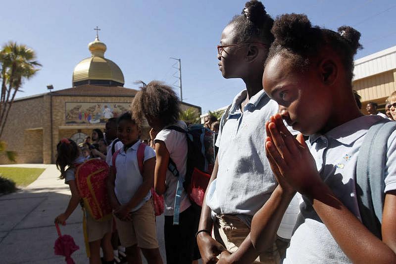 Zariyah Durant (left), 10, and her sister Zaniyah, 8, line up for the prayer at the end of the day at The School of the Immaculata in St. Petersburg. The girls switched to the private school after a revolving door of teachers at Maximo.