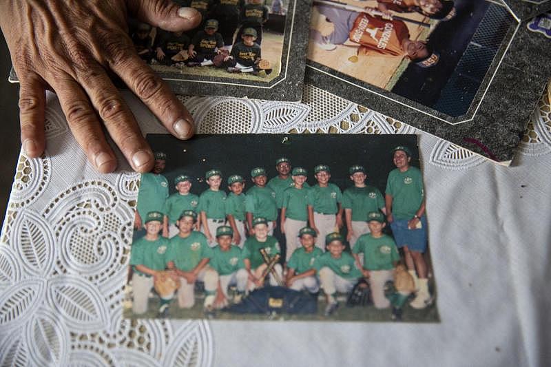 Theresa Martinez shows old photographs of her kids in Little League in Bloomington.