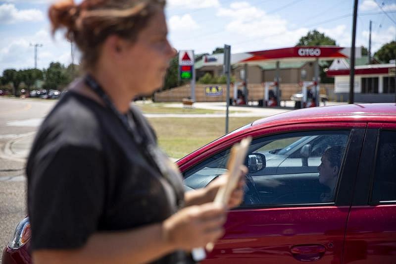 A driver stopped at a red light ignores Devan Orsak, 37, who holds a sign that says “Need Gas.” Orsak said drivers often ignore, stop far away, roll up windows and, on one occasion, throw food at her. Even though she and her seven children are no longer homeless, Orsak says she must continue to panhandle to pay for food, gas and other basic needs for her family until she finds a steady job.