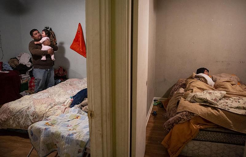 Jonathan Sanchez Salas, 33, holds his 7-month-old daughter, Kassidy Sanchez, while his wife, not pictured, tucks son Fernando Martinez, 9, into bed with his brother, who is already under the blankets. Fernando wears a hoodie and jeans to bed. The family was forced to move from their apartment after it and their belongings bore extensive damage from Hurricane Harvey. They lived in a single room at Crossroads Apartments before Sanchez Salas’ boss offered to rent them their current home, which is also in need of repair after the hurricane.