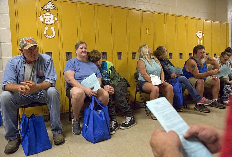 Folding chairs line a hallway at Lee County High School during a RAM Clinic in September, filled with people waiting for vision care. Michael Mannon, 50, of Jonesville and Michelle Ely, 48, and her 12-year-old son, Michael Ely, who live in Dryden, move along the chairs as they wait to enter a classroom and have their vision checked. 