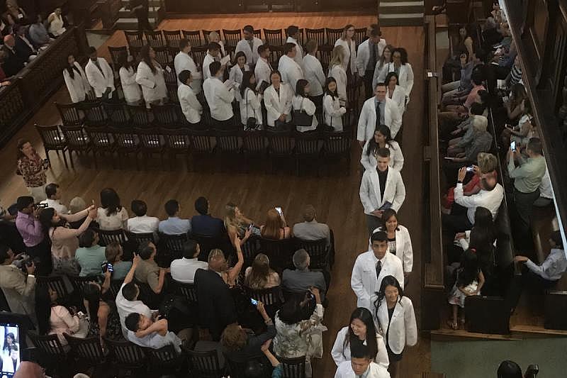 The inaugural class of the California University of Science and Medicine exits in procession after donning their white coats.
