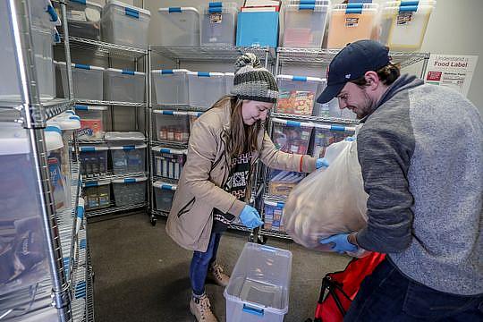 Henny Ransdell, left, and Ryan Buckman, right, take a bag of bagels donated by Einstein Bros. bagels, and put them into a plastic bin at U of L's food bank. Jan. 28, 2019 (Photo: Michael Clevenger/Courier Journal)