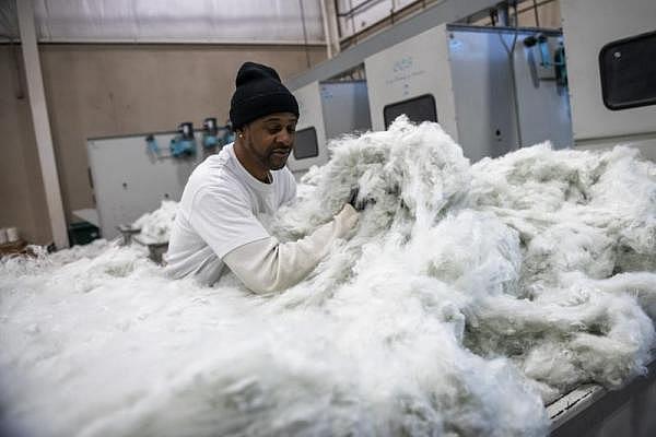 Melvin Peterson of Homestead separates recycled polyester used for pillows. (Michael M. Santiago/Post-Gazette)