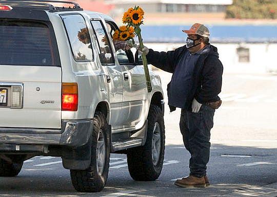 Isidoro Flores Contreras hands a customer a bouquet of sunflowers. He credits Herbalife with helping him walk again, and he believes it will also keep him safe from the novel coronavirus. May 15, 2020. (Photo: Vernon McKnight / The Salinas Californian)