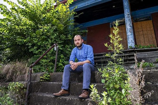 Artist Nathan Van Patter sits on the steps of an abandoned home, June 26 on Middle Street in North Braddock.