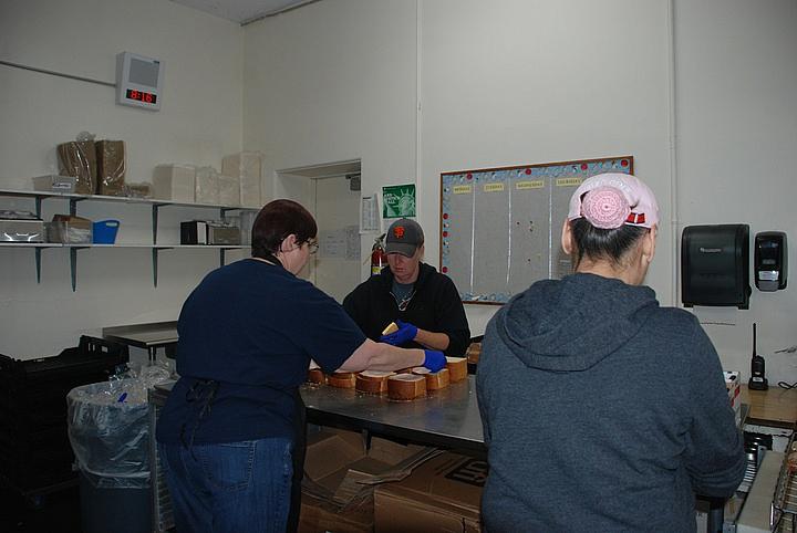 Lori Ekkart, Trina Lovdahl and Loni Salvaressa prepare 890 turkey and cheese sandwiches at the Crescent Elk Middle School kitchen Monday.
