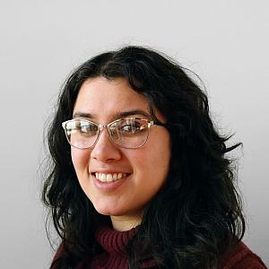 A person with clear glasses, black hair and red sweater