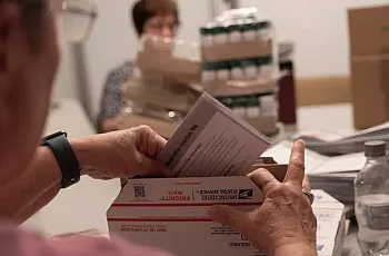 Volunteers at an abortion pill provider work around a conference table to pack 500 boxes to be sent to people in all 50 states. 