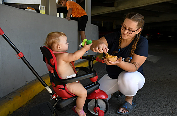 Person kneeling by a child in a stroller