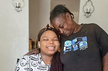 A Black woman embraces her granddaughter, who wears a prosthetic leg, in their Kern County home.