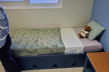 Bed with stuffed bear on it