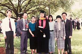 Group of people, one of whom is in a graduation cap and gown