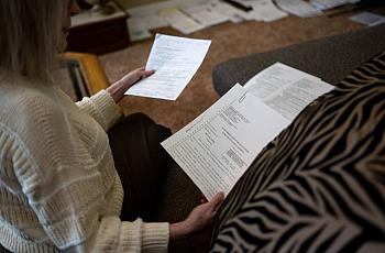 Elaine Sheffer, in her home in Sacramento, reviews paperwork related to her stepdaughter, a nonverbal autistic woman who receives services from one of California's 21 regional centers that serve people with developmental disabilities.