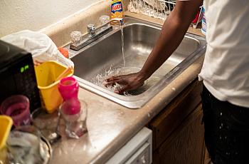 A man washes his hand in the sink.