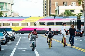 Teens ride bikes down a busy street.