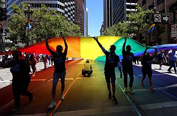 Marchers carry a pride flag down the street.