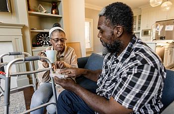 2 people discussing, one holding a medicine box