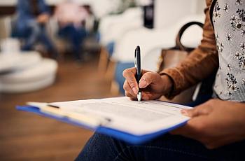 A woman fills out forms at a medical office.