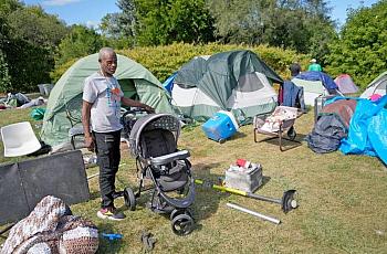 Person standing by tents set up on grass