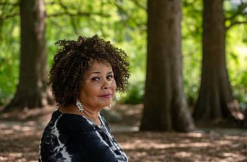 Image of a black woman sitting in front of trees