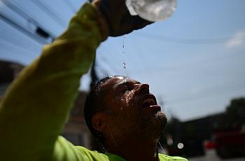 A man throwing water on his face for relief from the sun's heat.