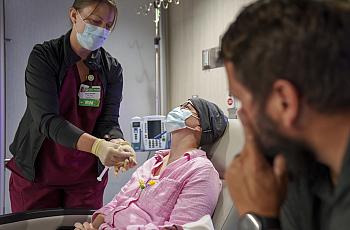 A nurse administrating medicines to a patient while a visitor watches