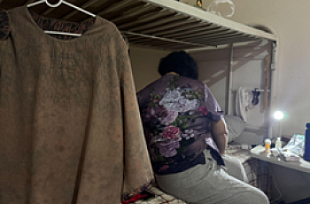 A person sitting on a bed facing away