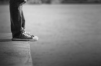 A black and white picture of legs with sneakers