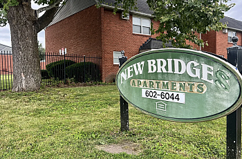 Lawn in front of red brick buildings with green sign