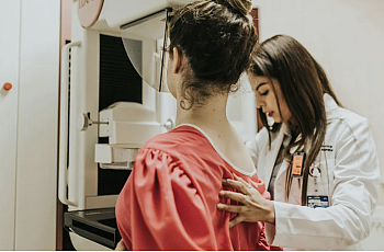 A female doctor helps another woman get a mammogram