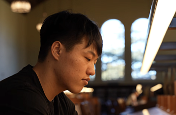 A young Korean man sits in a library