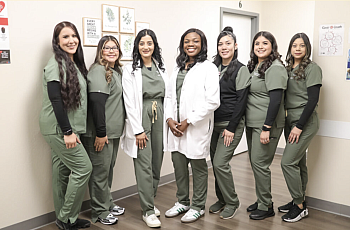 Dr. Ololade Oladimeji and her team pose at Peridot Health Medical clinic in their office wearing scrubs