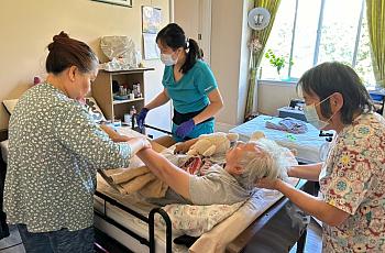 3 people assisting an elderly person