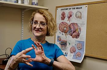 A lady trying to explain something in front of a brain diagram