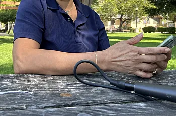 Image of a person sitting across the table in a park using their phone