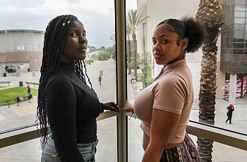 Chrishana Bunting, 16, and Lizette Pierce, 16, pose for a photo inside the Lincoln High School library in San Diego on Feb. 13, 2023. Both friends have experienced sexual comments about their bodies, treated like adults throughout their childhood, and received inappropriate comments about their skin tone. All examples of adultification bias and anti-Blackness. (Anissa Durham/ Word In Black)