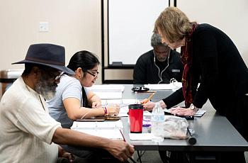A reading instructor helps a woman decode a series of words during an adult literacy class in Bellaire