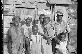 Multiple people standing in front of a wooden hut