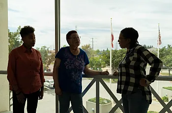 Three people standing over a balcony