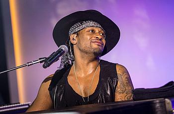 Person with hap and black top in front of a mic